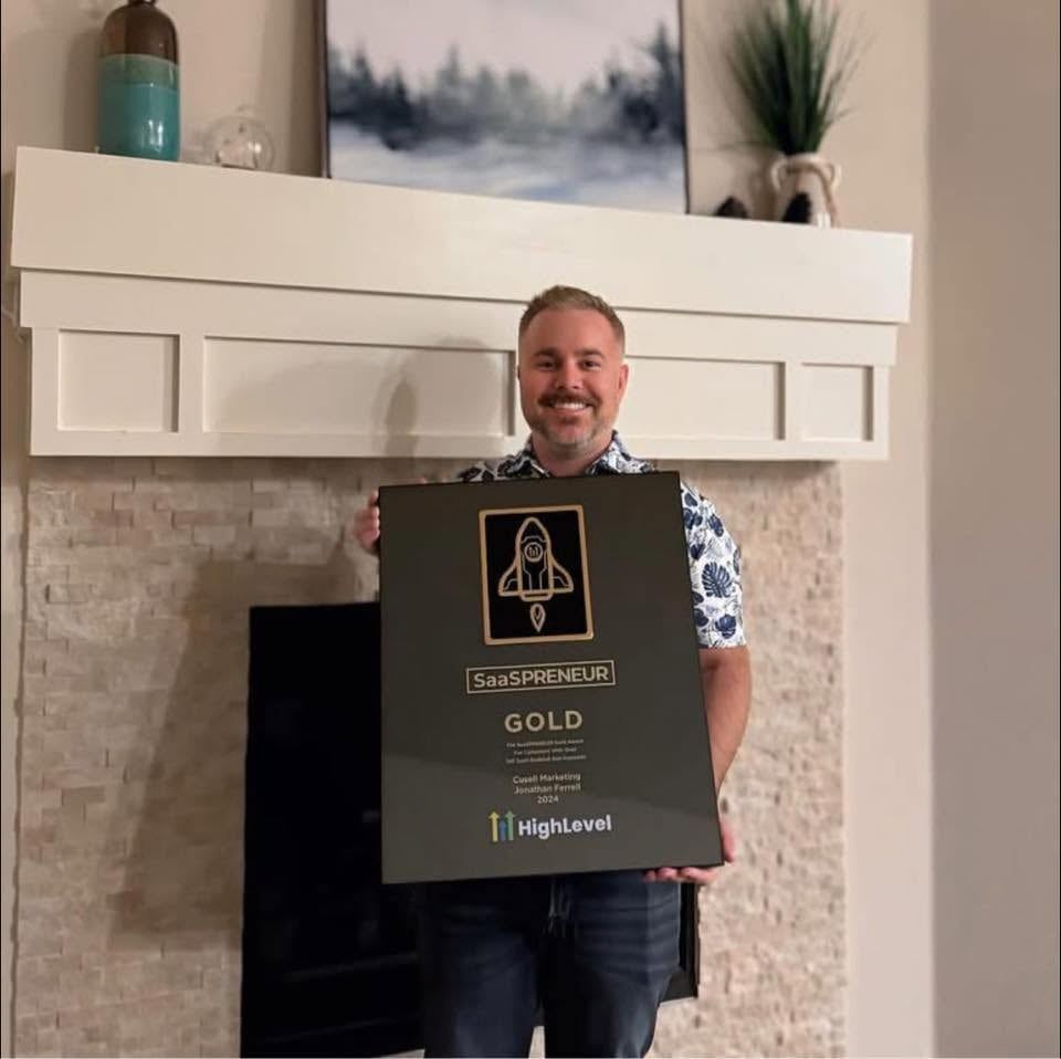 Jonathan Ferrell at home holding his HighLevel SaaSPRENEUR Gold award.