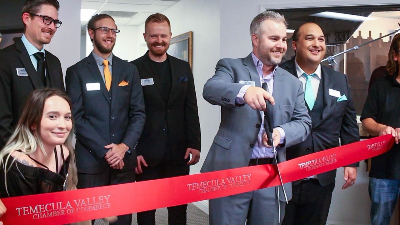 Jonathan cutting a Temecula Valley Chamber of Commerce ribbon while community members stand beside him.