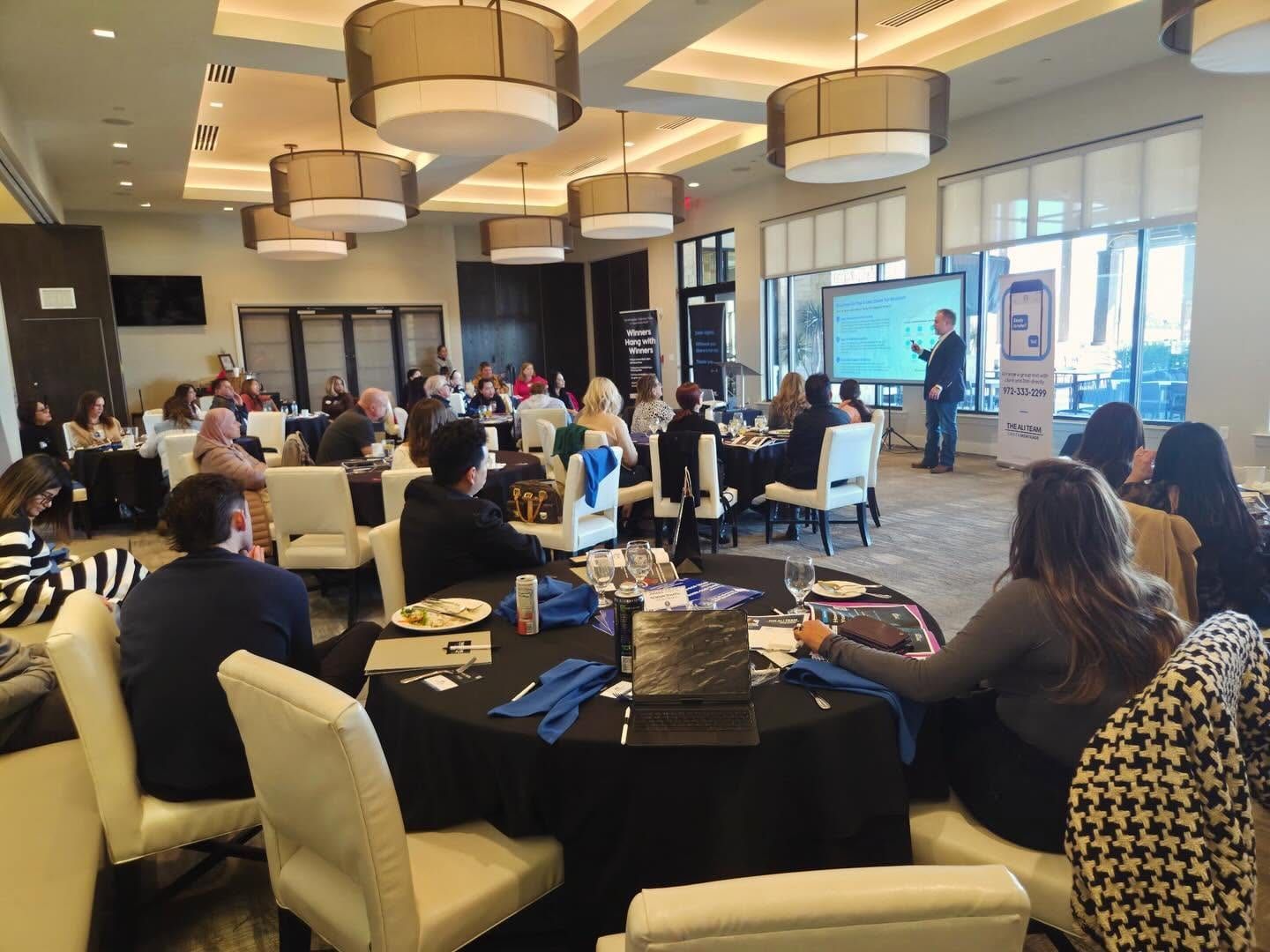 Jonathan presenting to a full room of guests seated around tables.