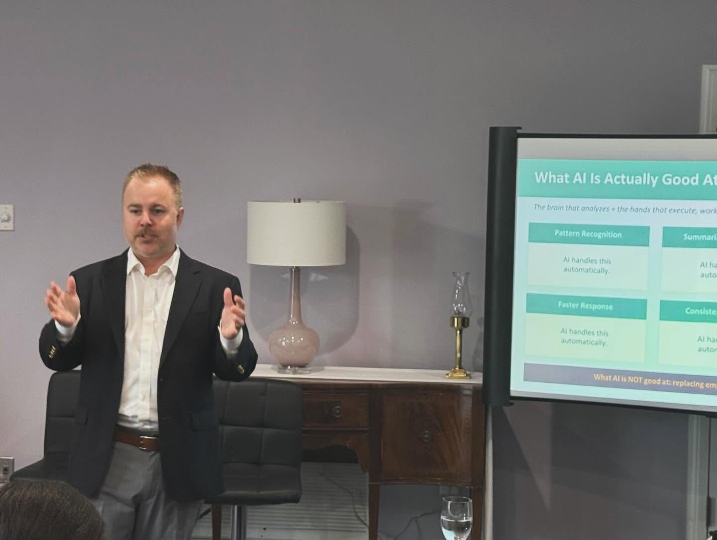 Jonathan mid-talk with both hands raised beside a slide titled What AI Is Actually Good At.